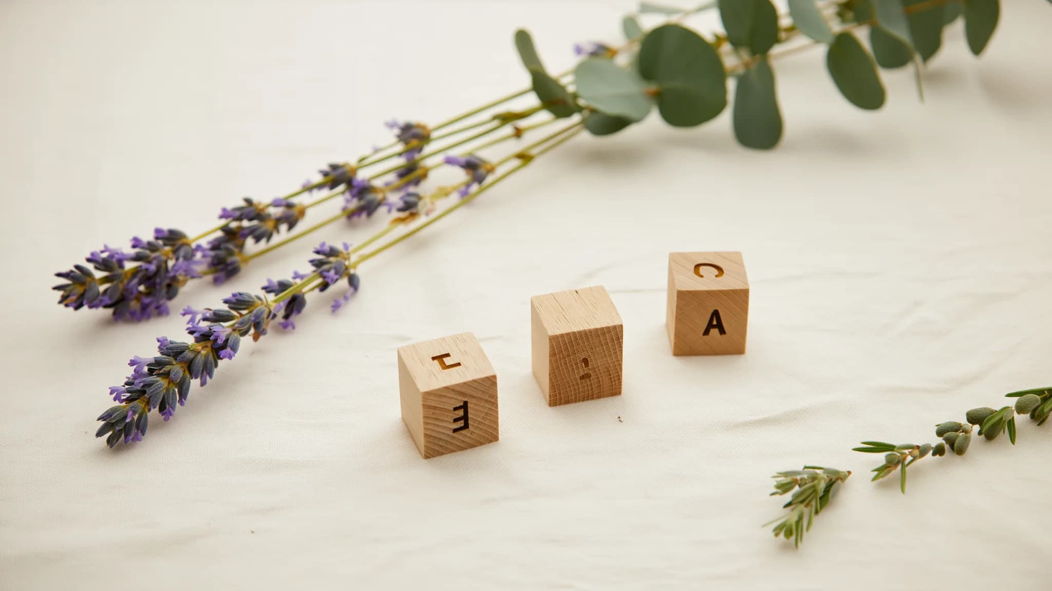 Holzbuchstaben-Blöcke buchstabieren kurze Namen auf cremefarbenem Leinen, mit getrocknetem Lavendel